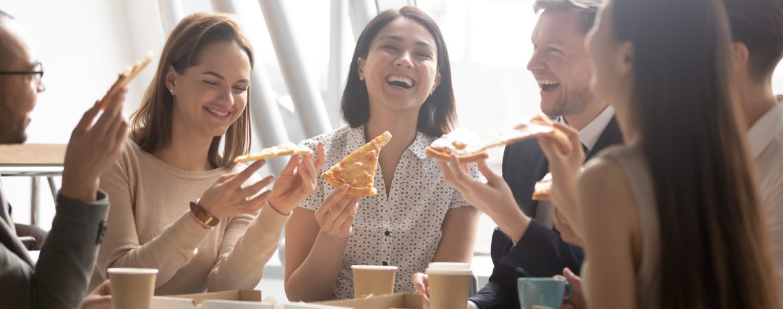 En gjeng kollegaer sitter sammen og spiser pizza.